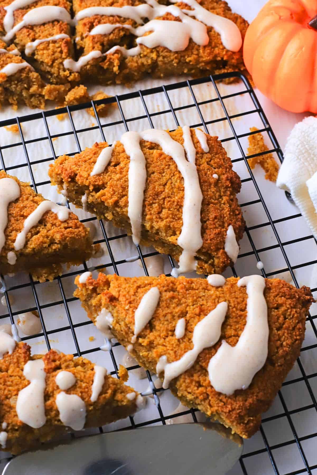 Gluten Free High Protein Low carb pumpkin spice scones drizzled with a glaze on a cooling rack.