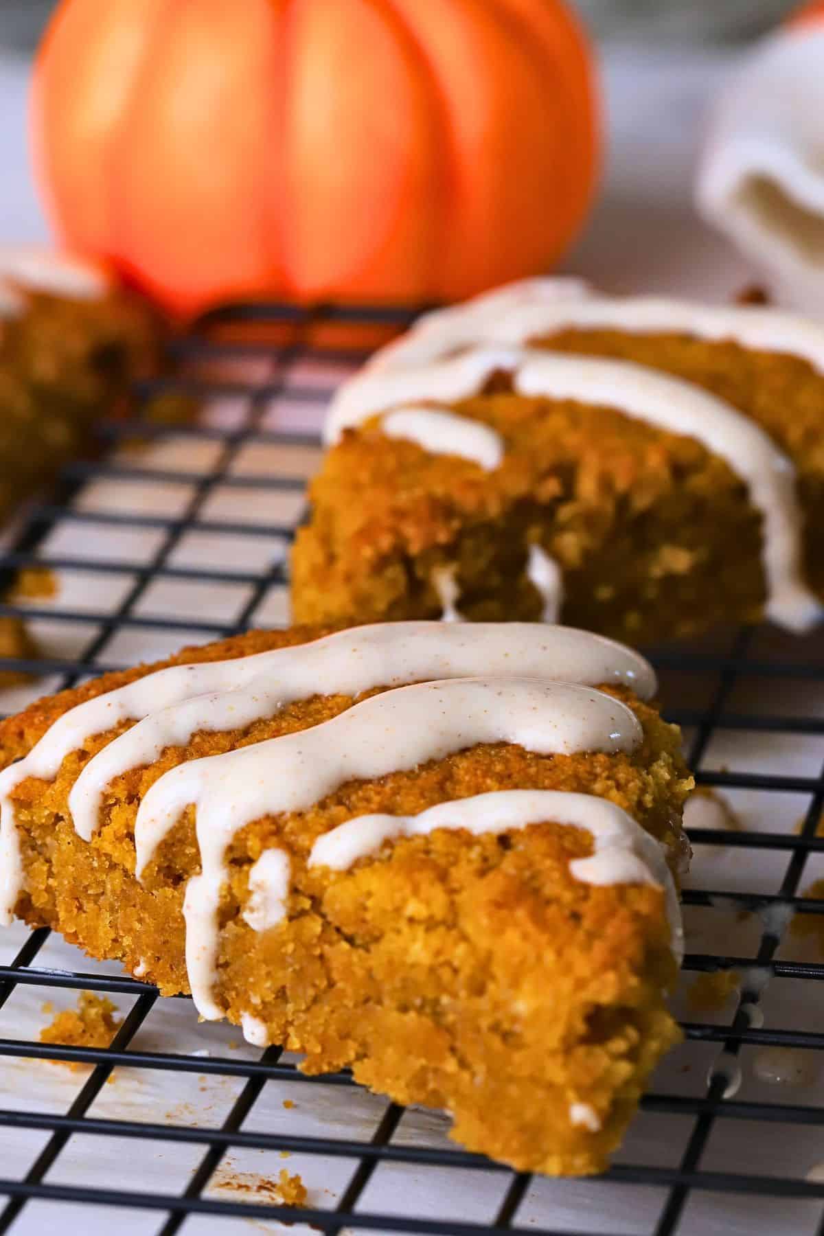 Gluten Free High Protein Low carb pumpkin spice scones drizzled with a glaze on a cooling rack.