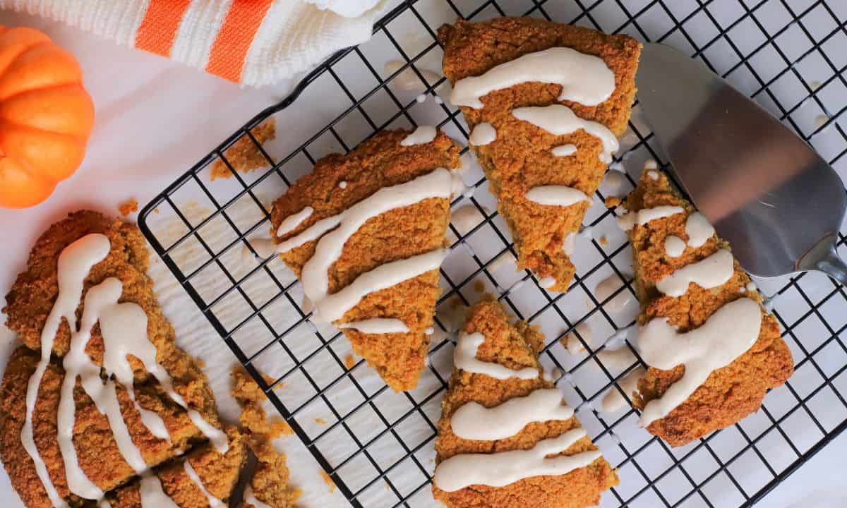 Gluten Free High Protein Low carb pumpkin spice scones drizzled with a glaze on a cooling rack.