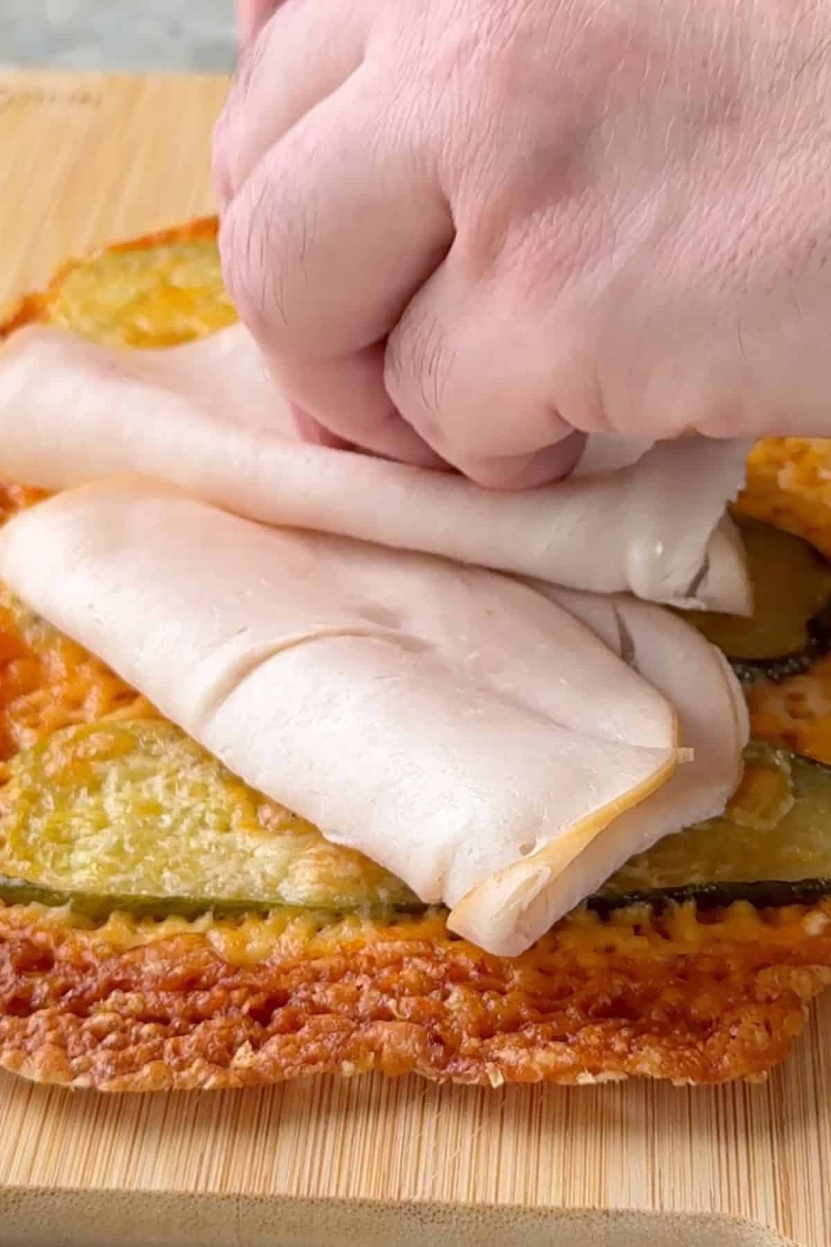 Placing the turkey slices on the pickle sandwich wrap.