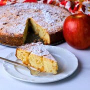 Low carb apple ricotta cake slice on a plate next to the cake.