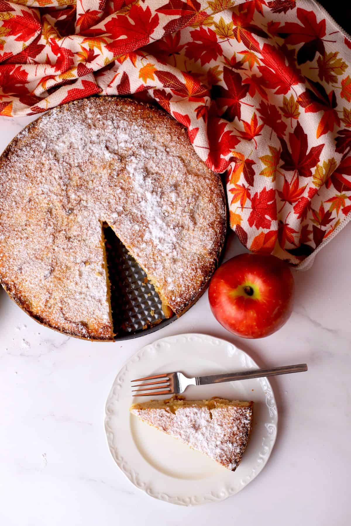 Low carb apple ricotta cake slice on a plate next to the cake.