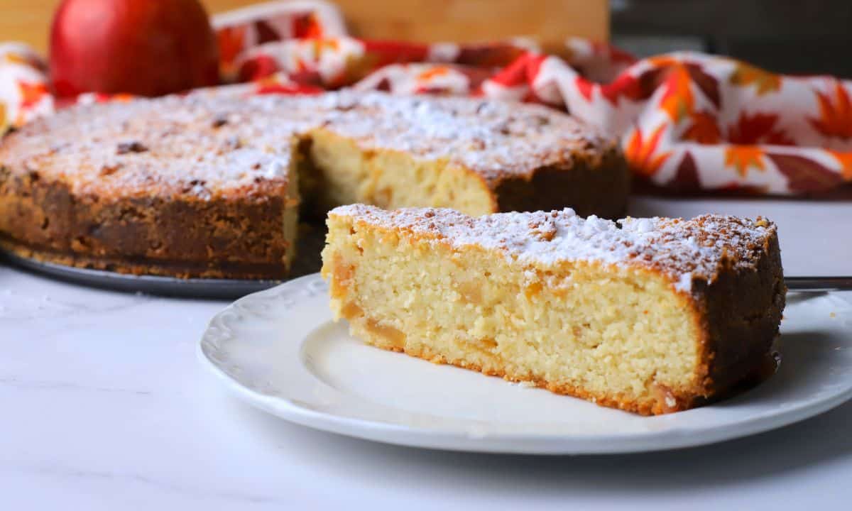 Low carb apple ricotta cake slice on a plate next to the cake.
