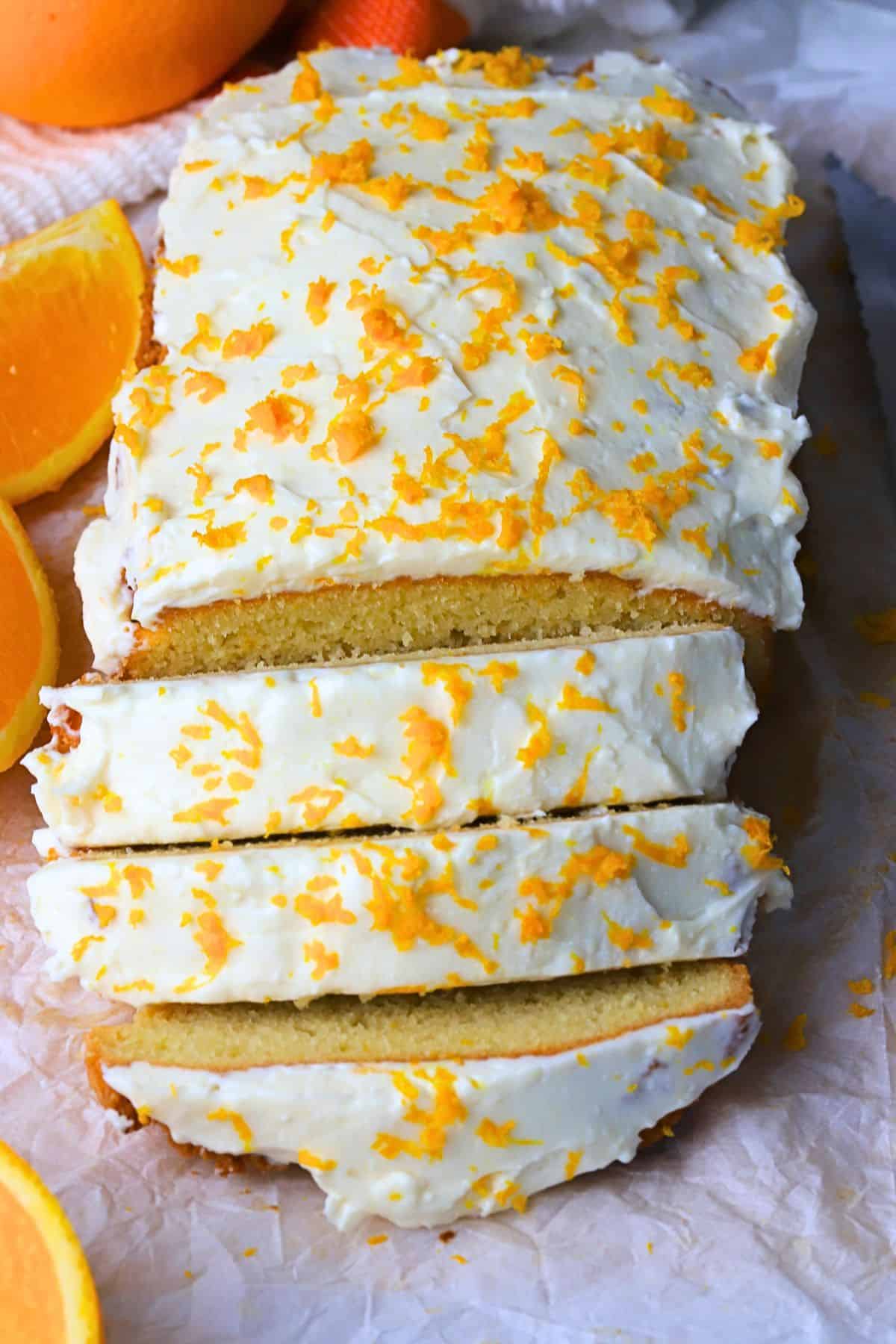 Low carb orange loaf cake cut into slices next to oranges.