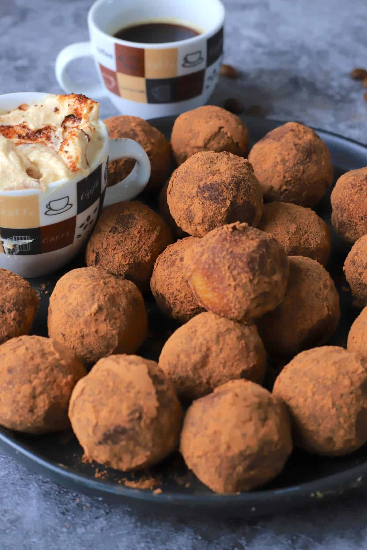 Low carb tiramisu protein balls on a plate next to the dip and a cup of coffee.