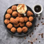 Low carb tiramisu protein balls on a plate next to the dip and a cup of coffee.