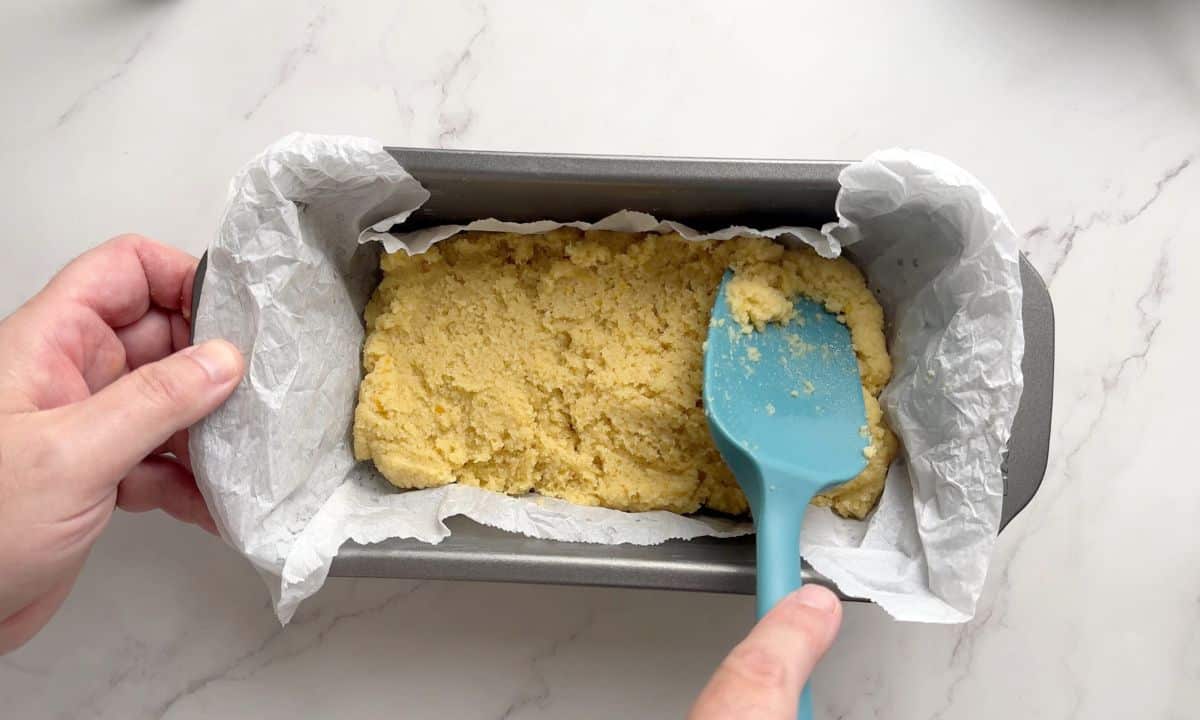 Transferring the orange loaf cake batter to the loaf pan.