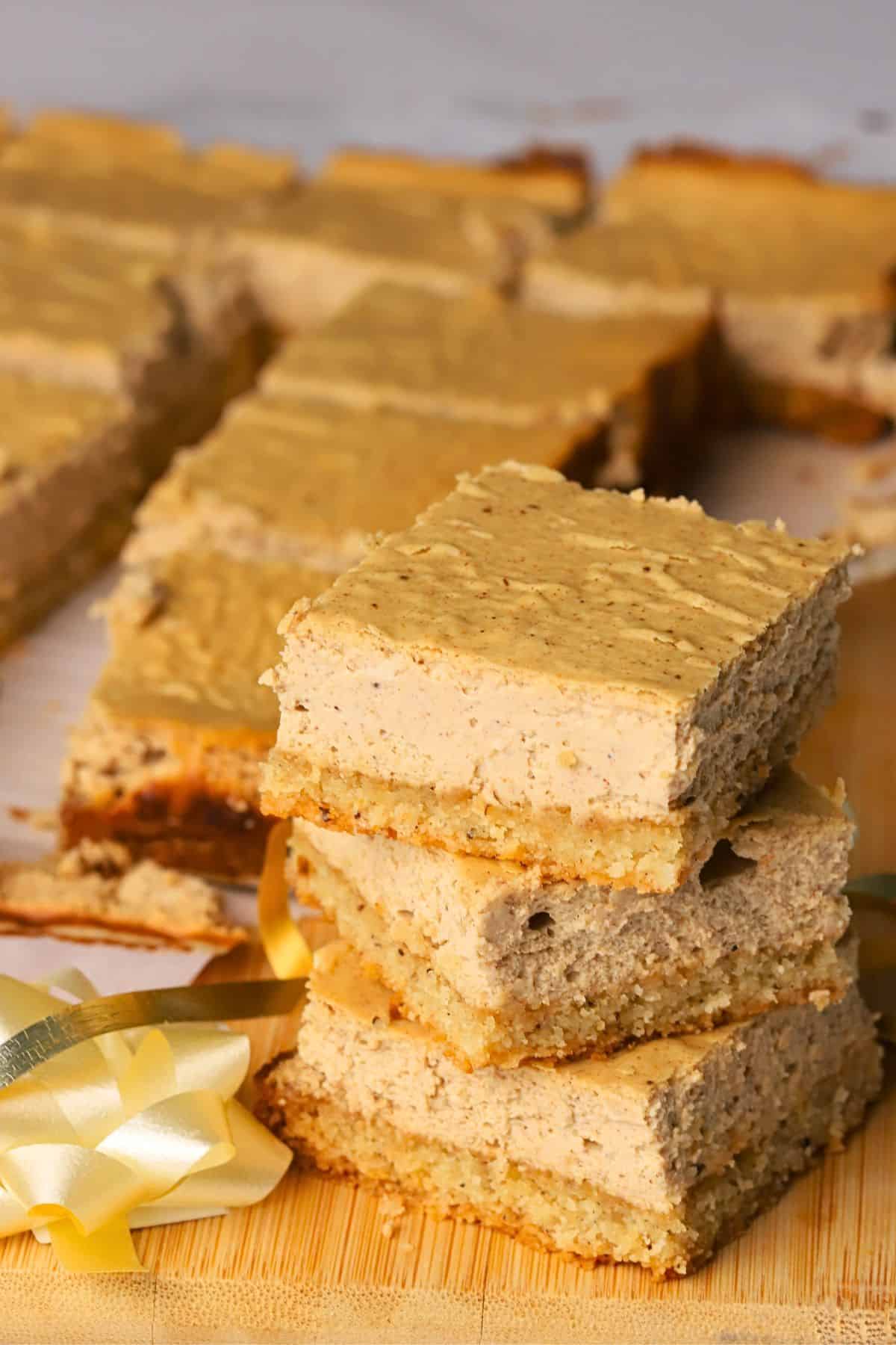 Low carb gingerbread cheesecake squares stacked on top of each other with more in the background.