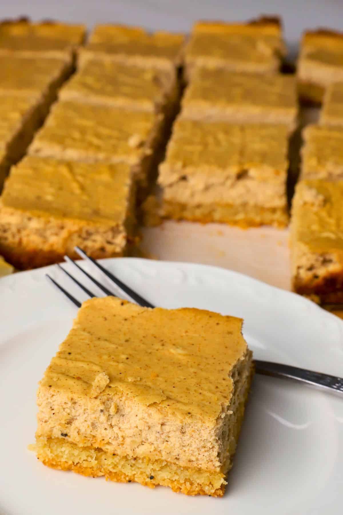 Low carb gingerbread cheesecake square on a plate with more squares behind it.