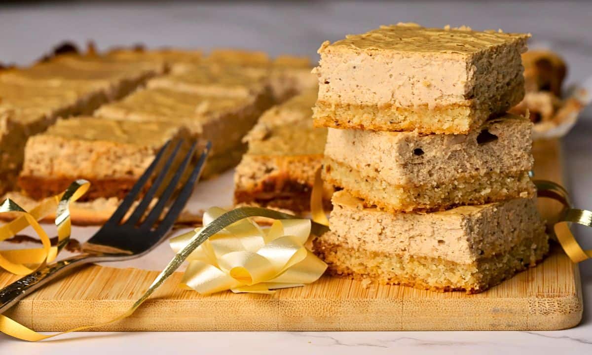 Low carb gingerbread cheesecake squares stacked on top of each other with more in the background.