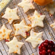 Low carb orange cranberry shortbread cookies on a cooling rack next to a bowl of cranberries and an orange.