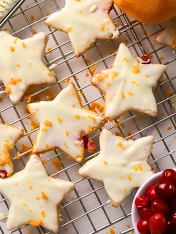 Low carb orange cranberry shortbread cookies on a cooling rack next to a bowl of cranberries and an orange.