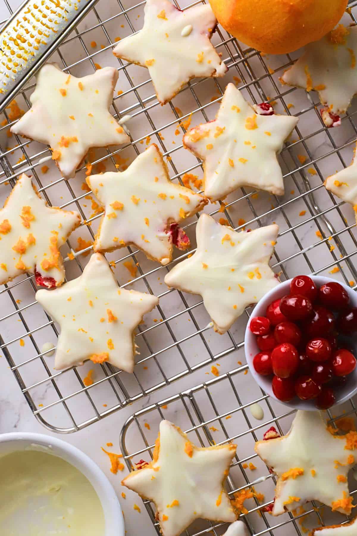 Low carb orange cranberry shortbread cookies on a cooling rack next to a bowl of cranberries and an orange.