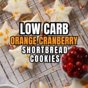 Low carb orange cranberry shortbread cookies on a cooling rack next to a bowl of cranberries and an orange.