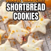 Low carb orange cranberry shortbread cookies on a cooling rack next to a bowl of cranberries and an orange.