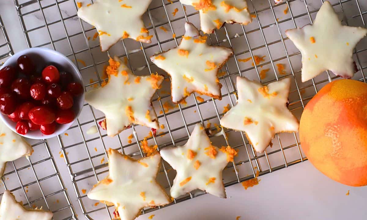 Low carb orange cranberry shortbread cookies on a cooling rack next to a bowl of cranberries and an orange.