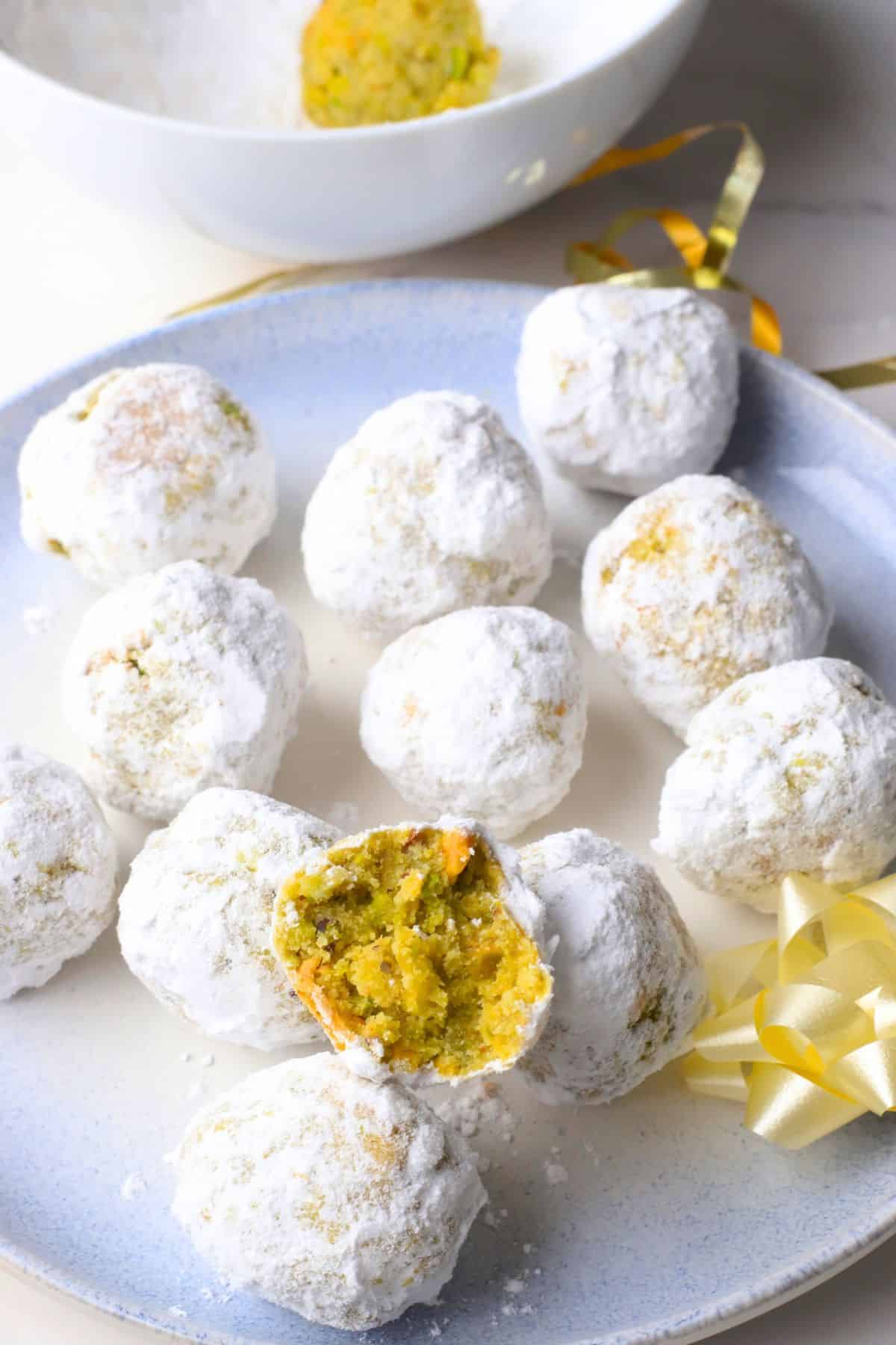 Low carb pistachio snowball cookies on a plate with one cookie with a bite in it.