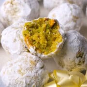 Low carb pistachio snowball cookies on a plate with one cookie with a bite in it.
