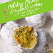 Low carb pistachio snowball cookies on a plate with one cookie with a bite in it.