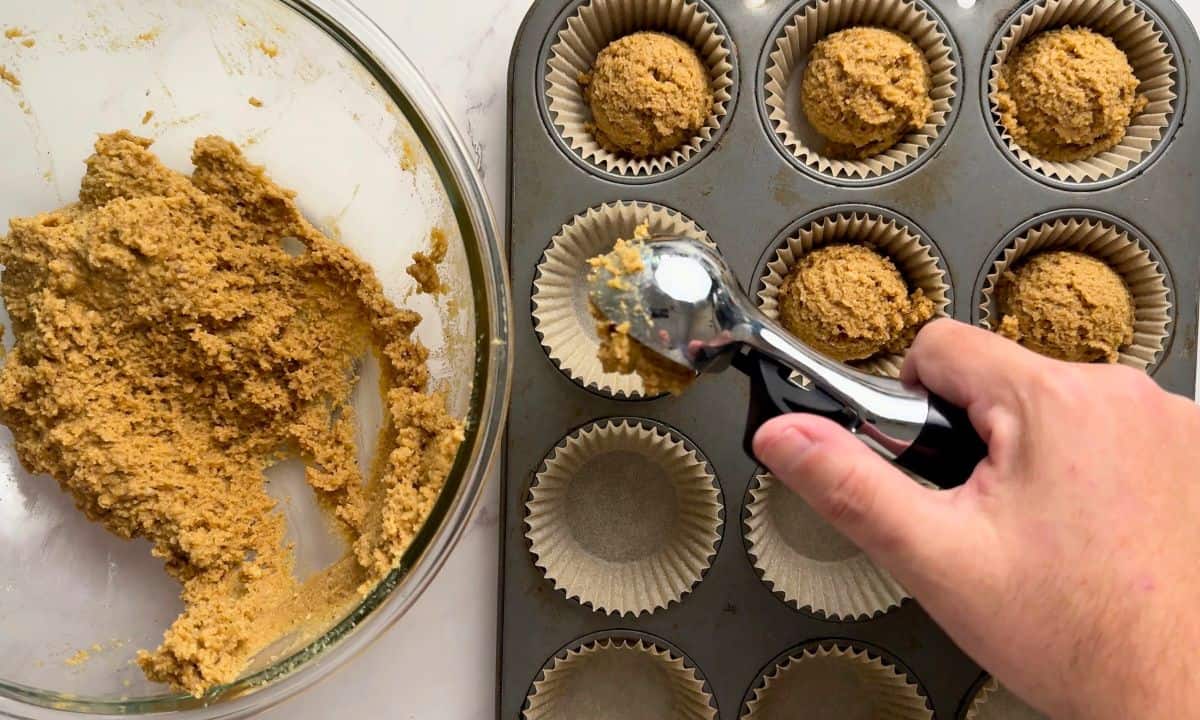 Scooping the muffin batter into muffin liners.