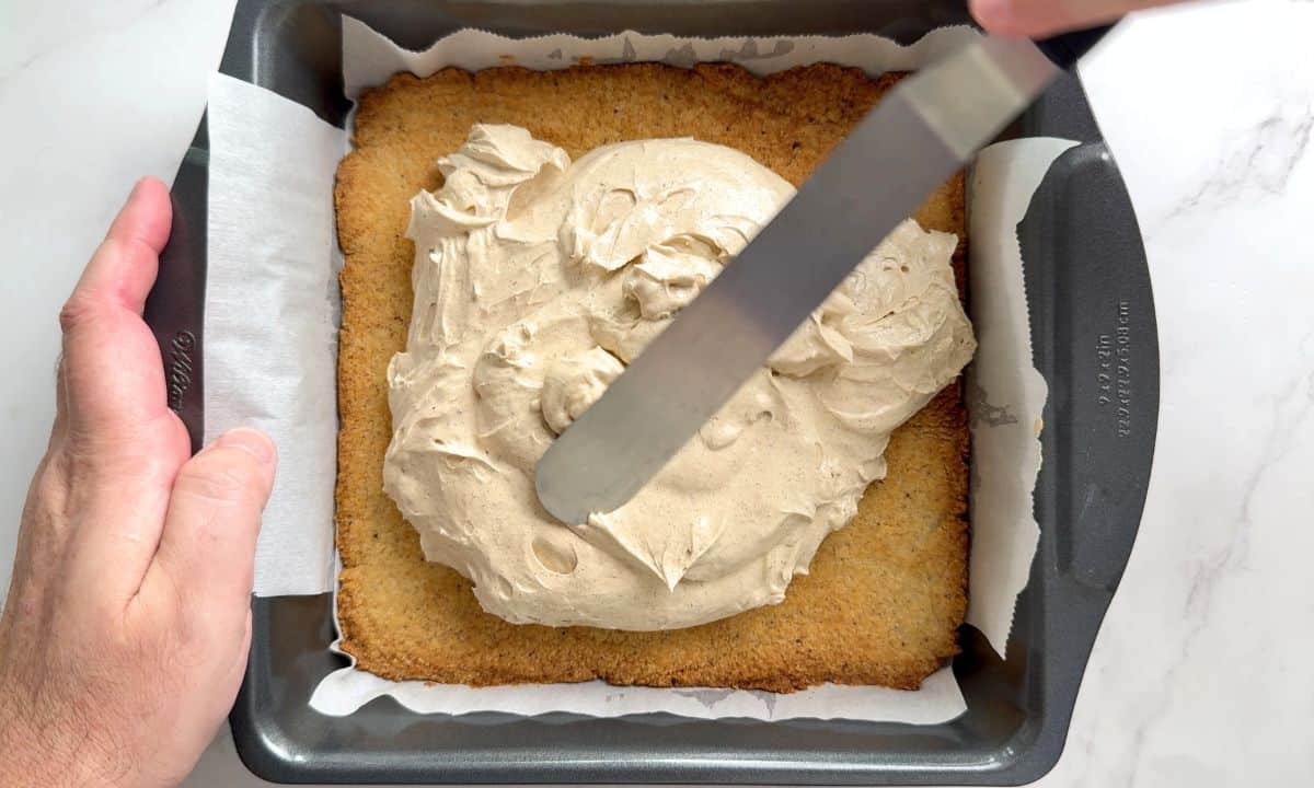 Spreading the cheesecake filling on top of the crust.