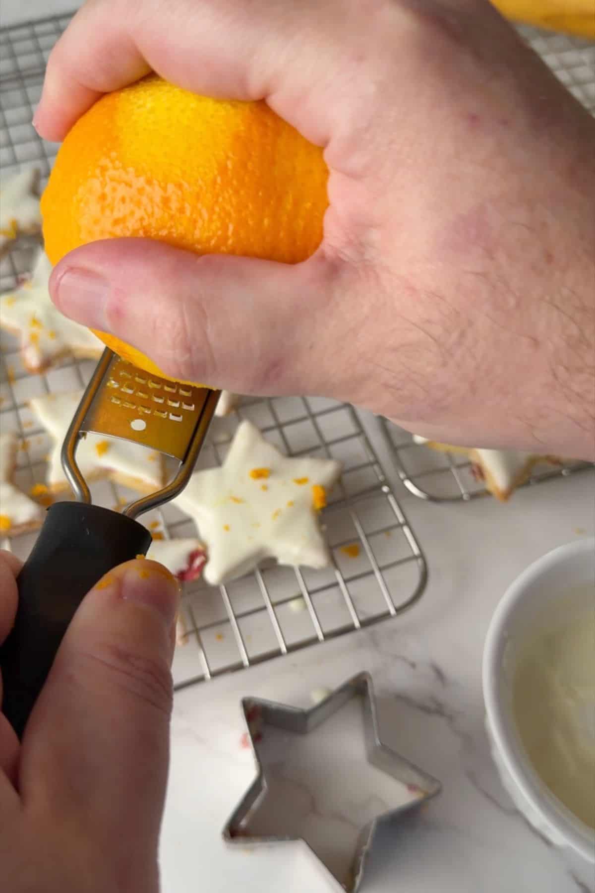 Zesting orange over the cookies.