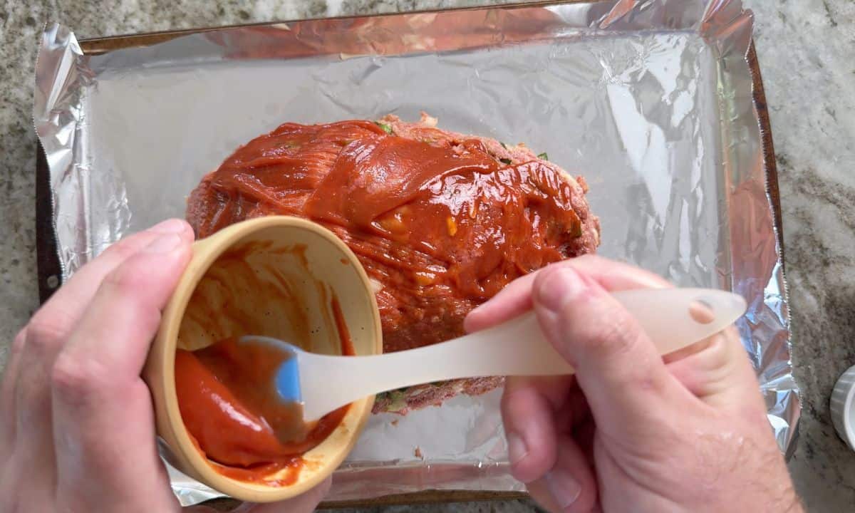Brushing the meatloaf with ketchup.