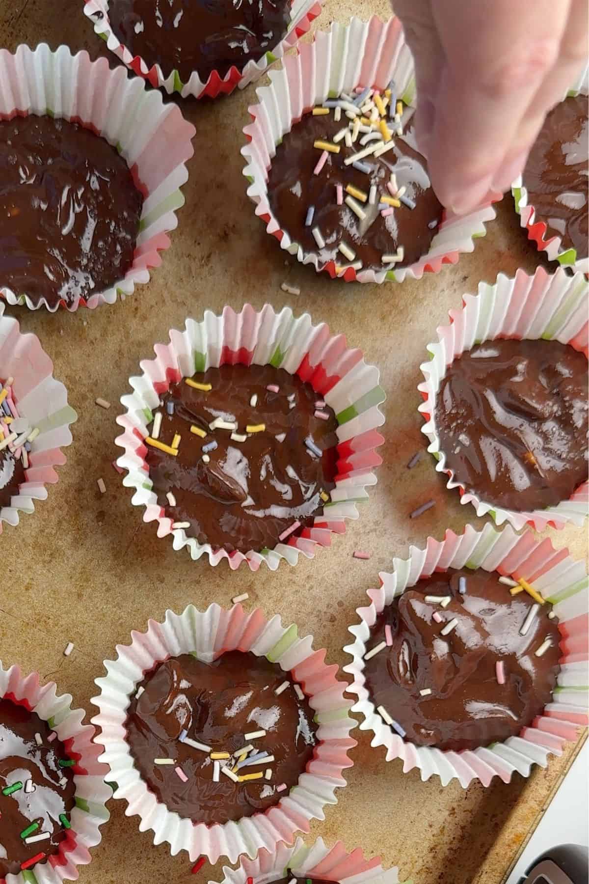 Adding sprinkles to the tops of the peanut clusters.