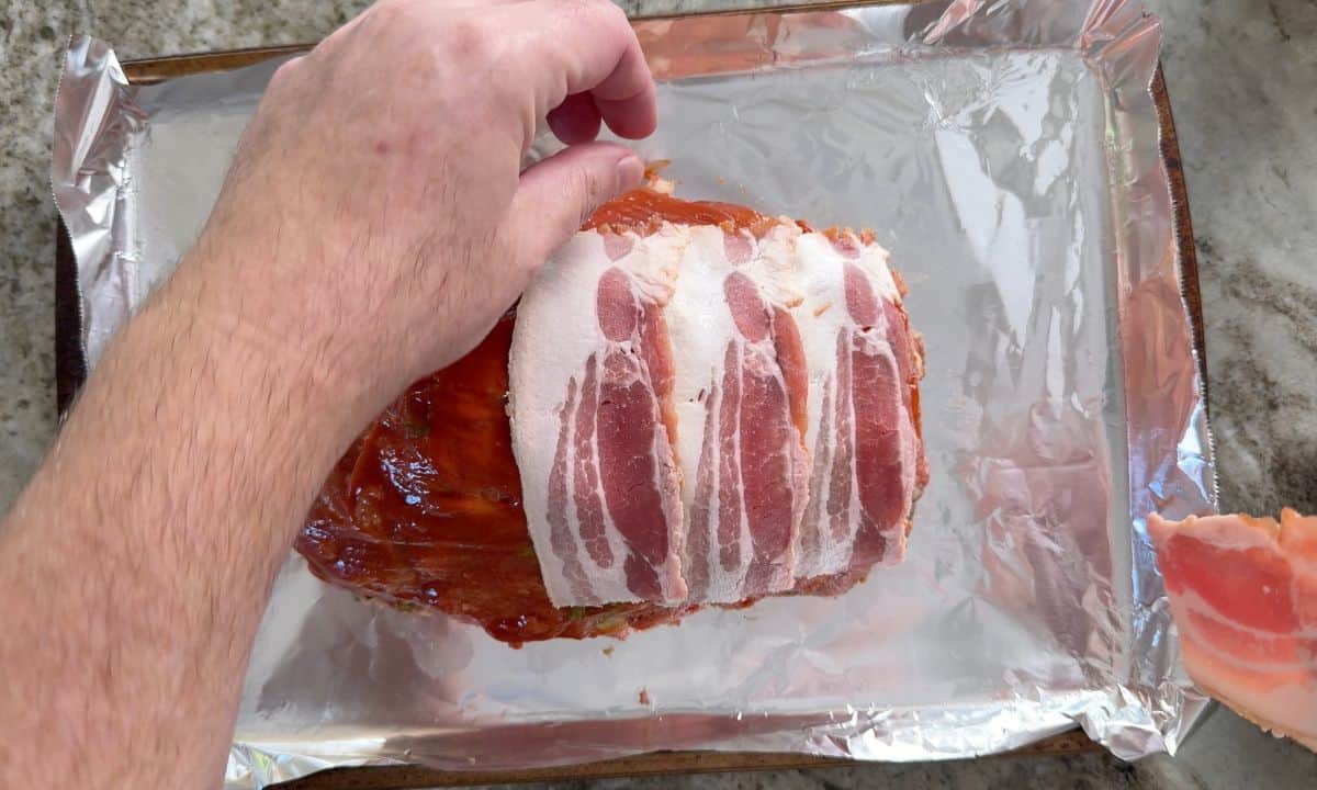 Wrapping the meatloaf with bacon strips.
