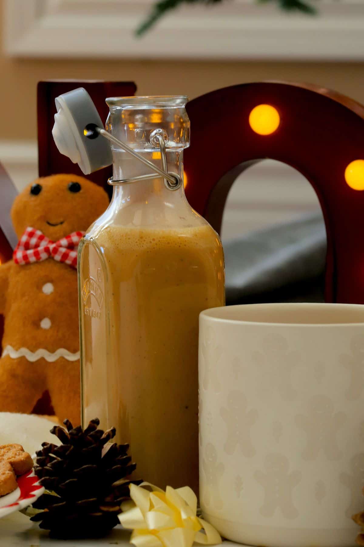 Homemade low carb gingerbread coffee creamer in a bottle next to a mug and other gingerbread men.