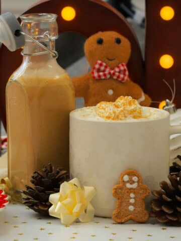 Homemade low carb gingerbread coffee creamer in a bottle next to a mug and other gingerbread men.