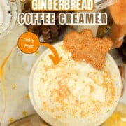 Coffee mug topped with whipped cream and a gingerbread man cookie on top.