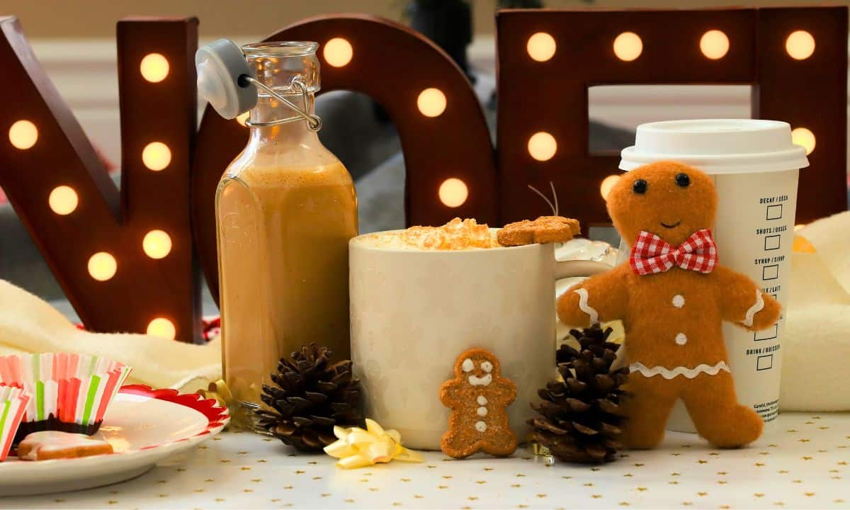 Homemade low carb gingerbread coffee creamer in a bottle next to a mug and other gingerbread men.
