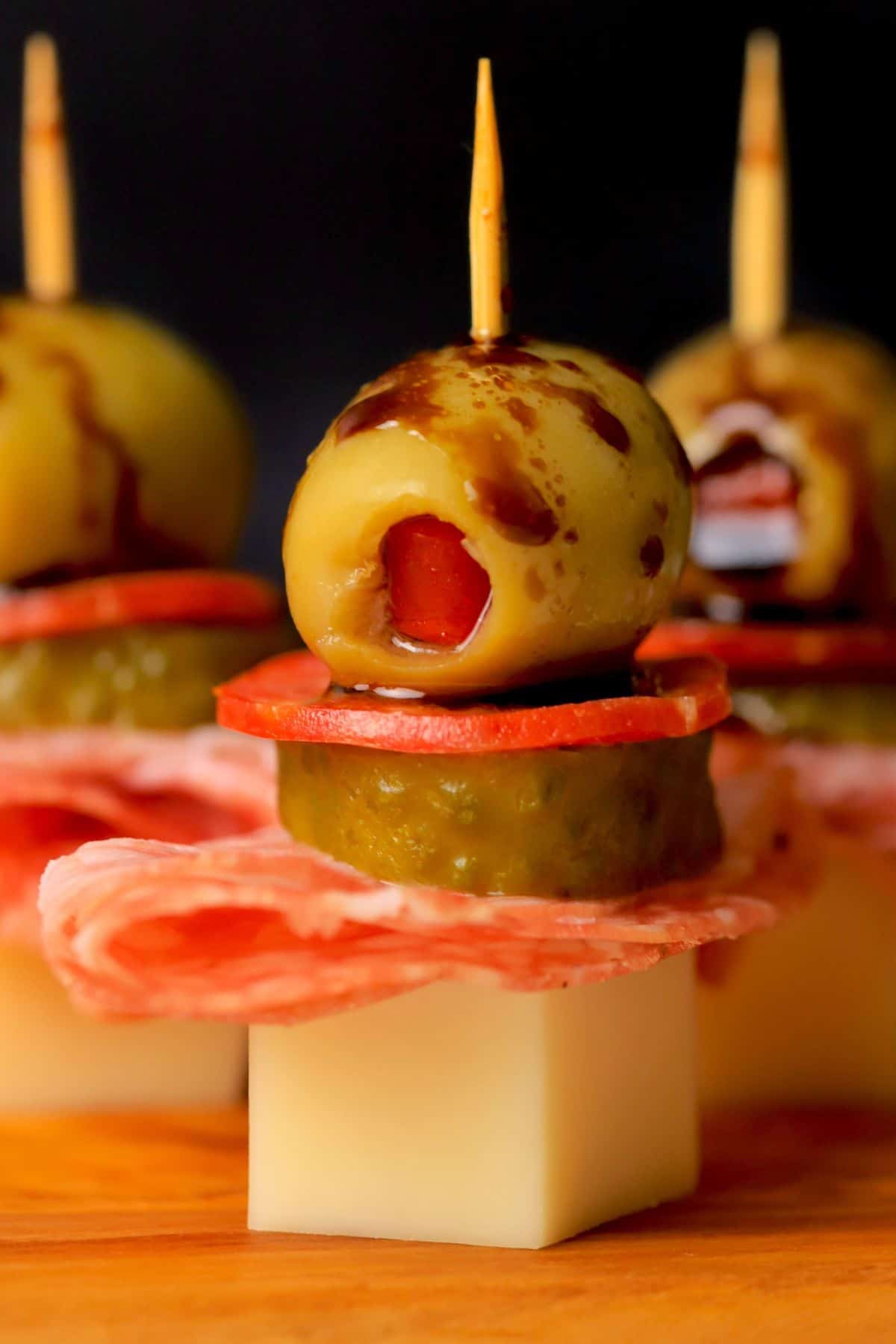 Italian sub skewers with a balsamic olive oil drizzle on a cutting board.