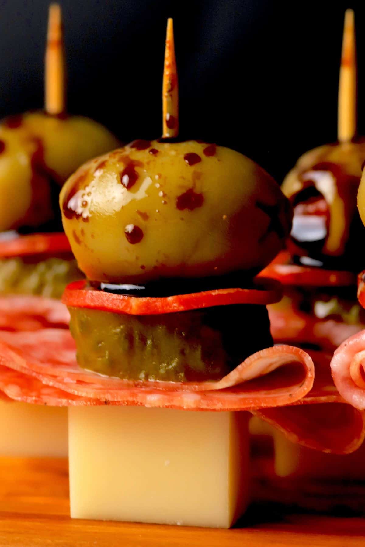 Closeup of Italian sub skewers with a balsamic olive oil drizzle on a cutting board.