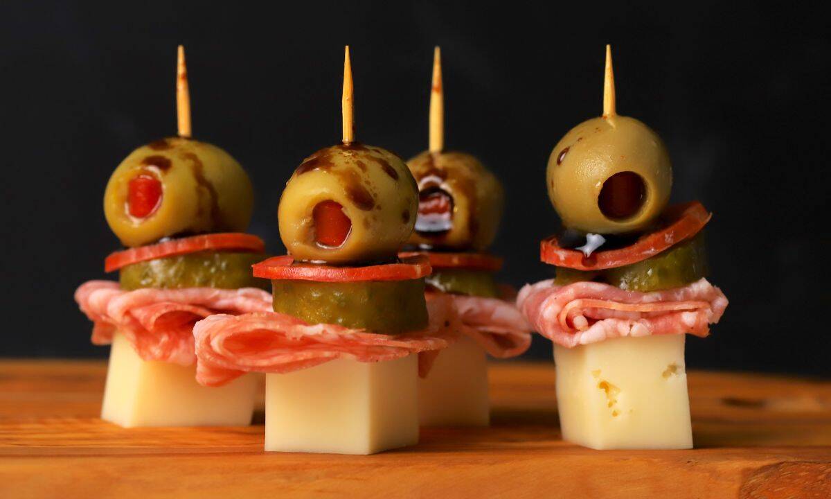 Italian sub skewers with a balsamic olive oil drizzle on a cutting board.