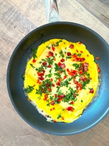 Low carb crispy pancetta open faced omelette in a skillet.