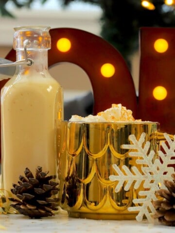 Low carb eggnog coffee creamer in a mug next to a bottle of the dairy free creamer.