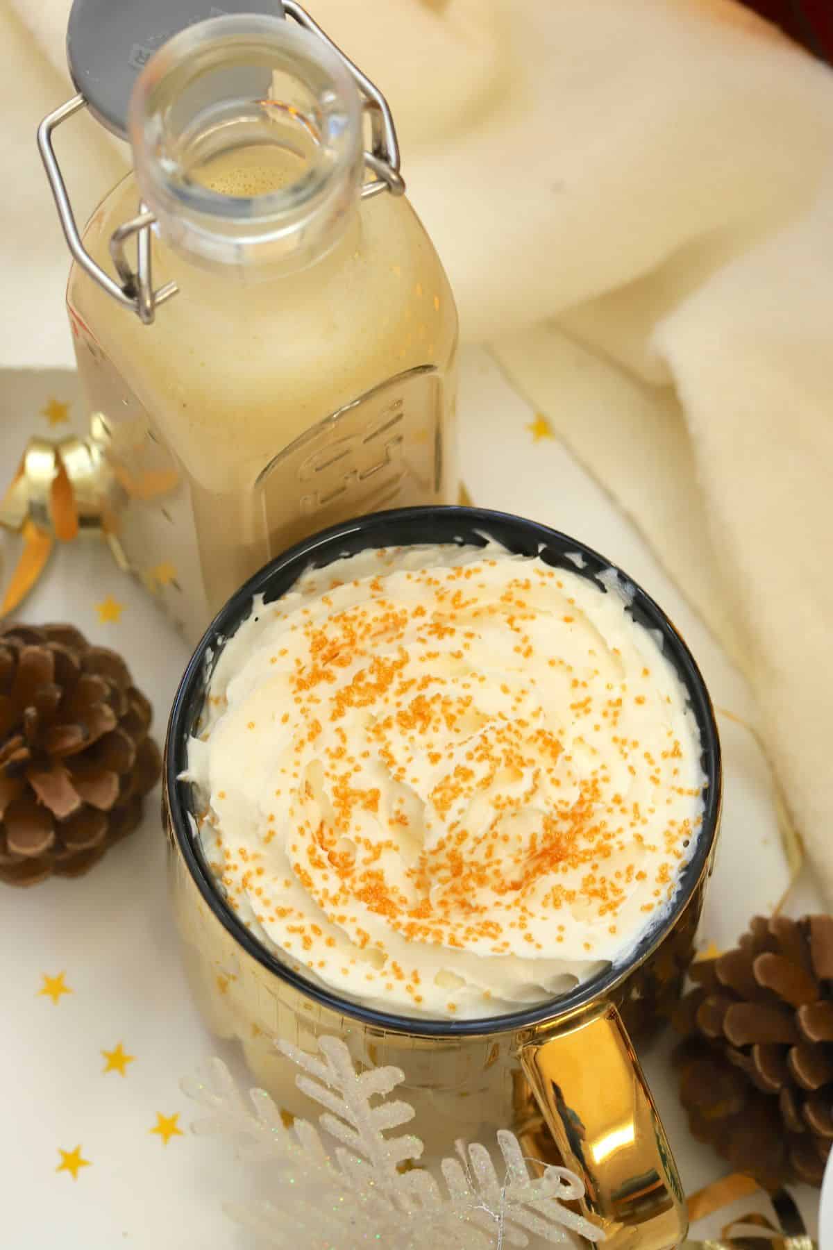 Low carb eggnog coffee creamer in a mug next to a bottle of the dairy free creamer.