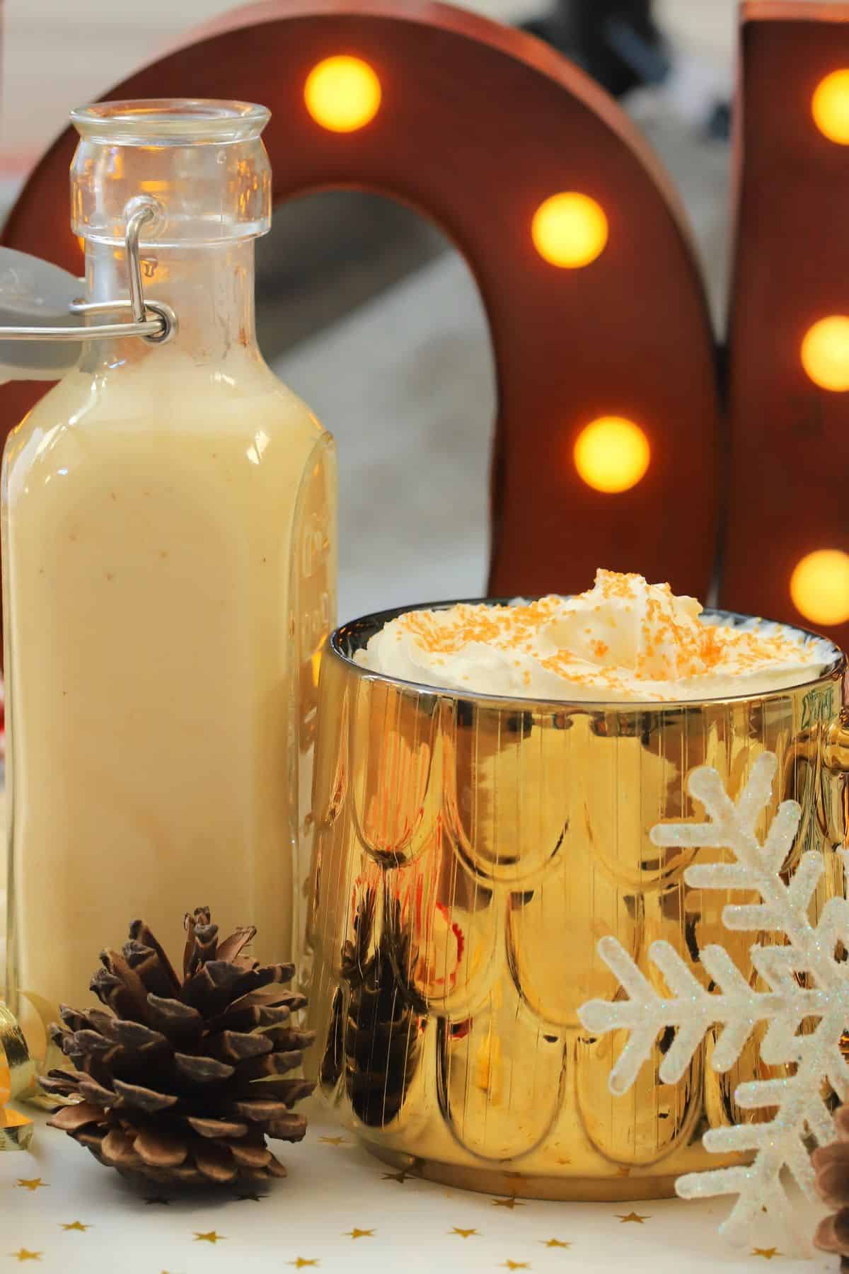 Low carb eggnog coffee creamer in a mug next to a bottle of the dairy free creamer.