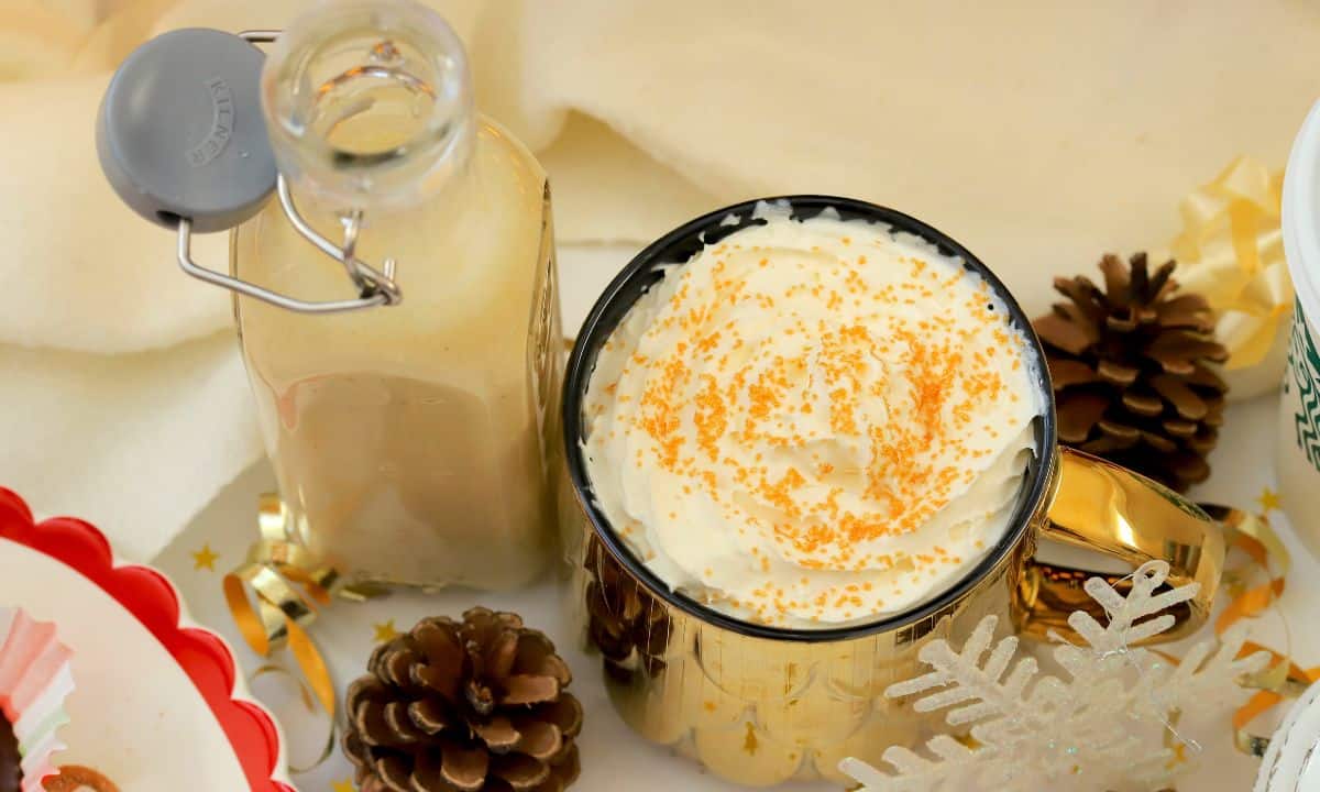 Low carb eggnog coffee creamer in a mug next to a bottle of the dairy free creamer.