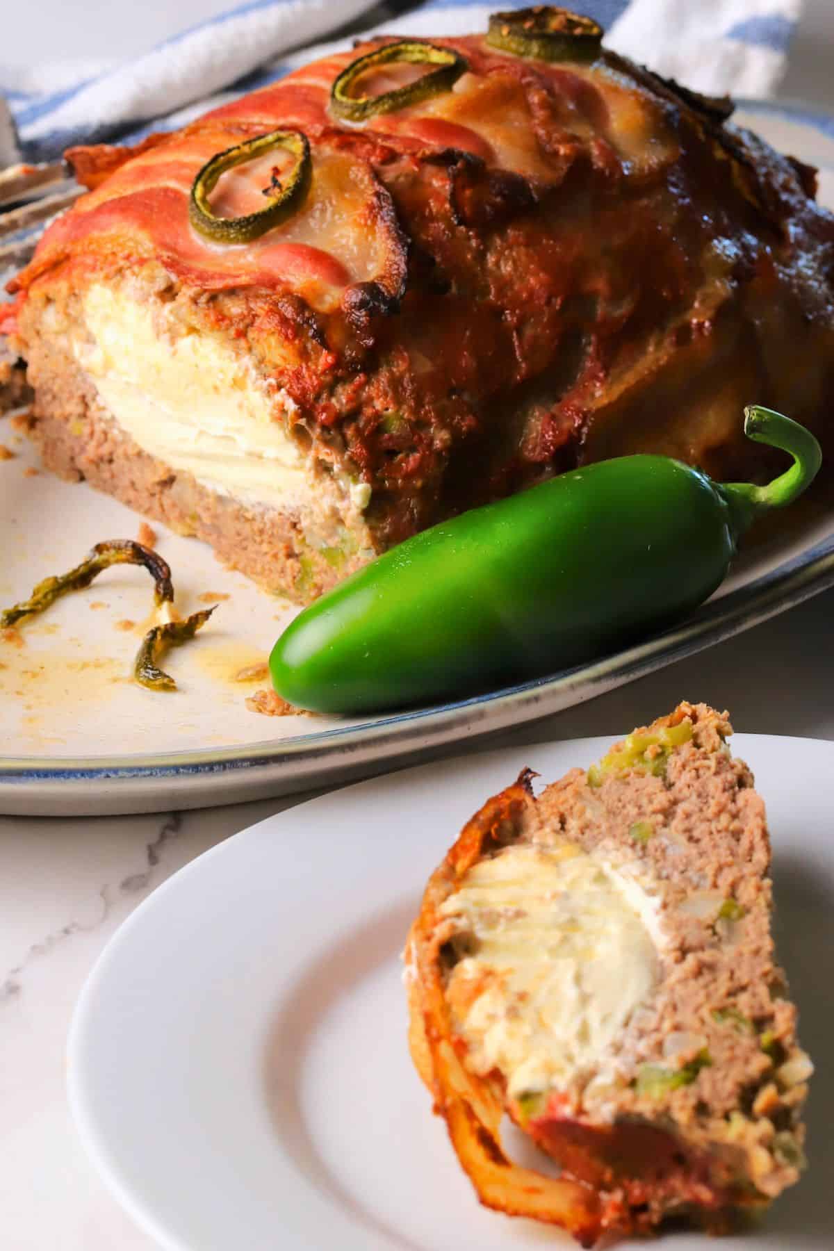 Low carb jalapeno popper meatloaf on a platter with a slice on a plate.
