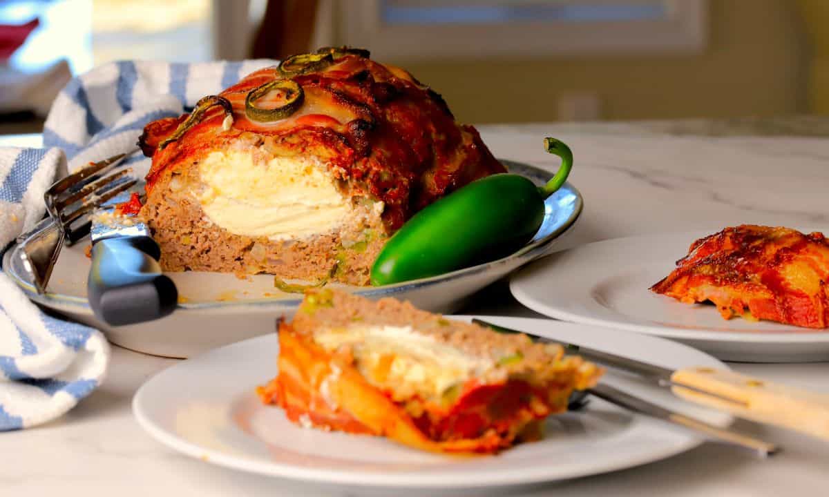 Low carb jalapeno popper meatloaf on a platter with a slice on a plate.