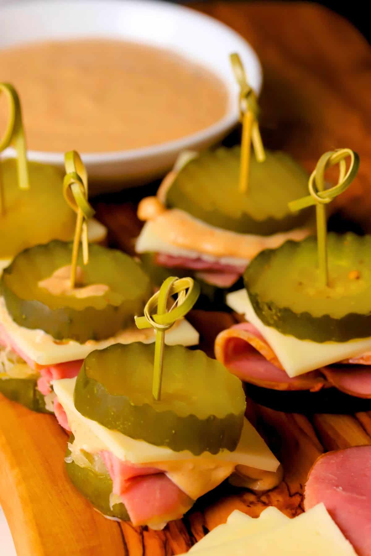 Low carb reuben pickle bites on a cutting board next to the russian dressing.