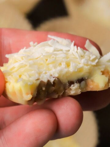 Holding a low carb white chocolate pecan coconut cluster.