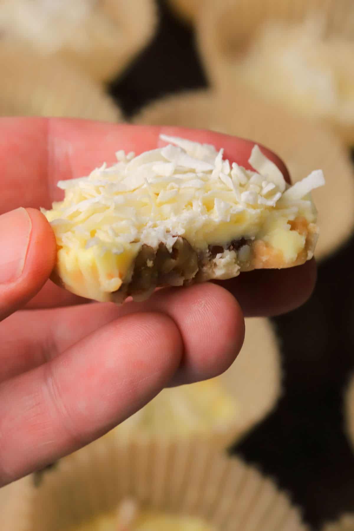 Holding a low carb white chocolate pecan coconut cluster.