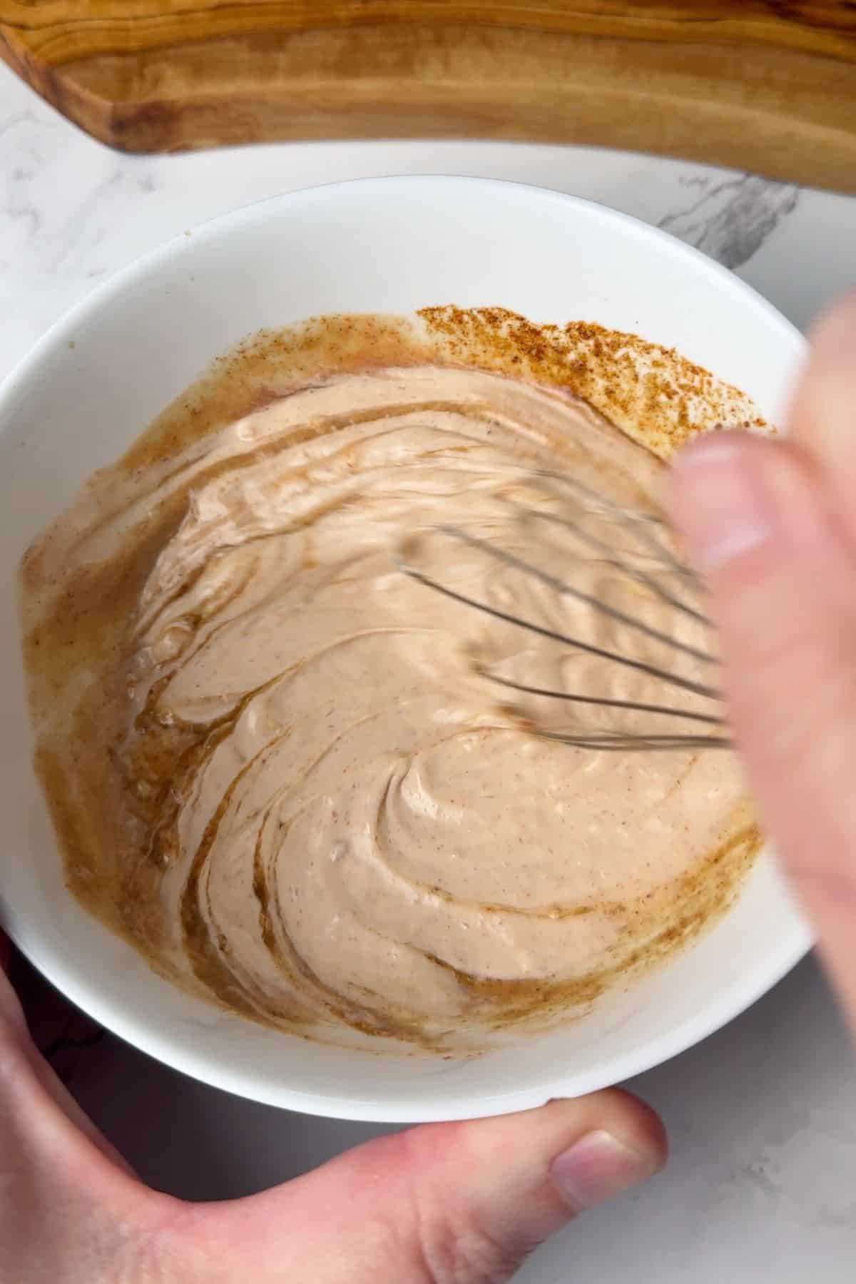 Whisking the russian dressing in a bowl.
