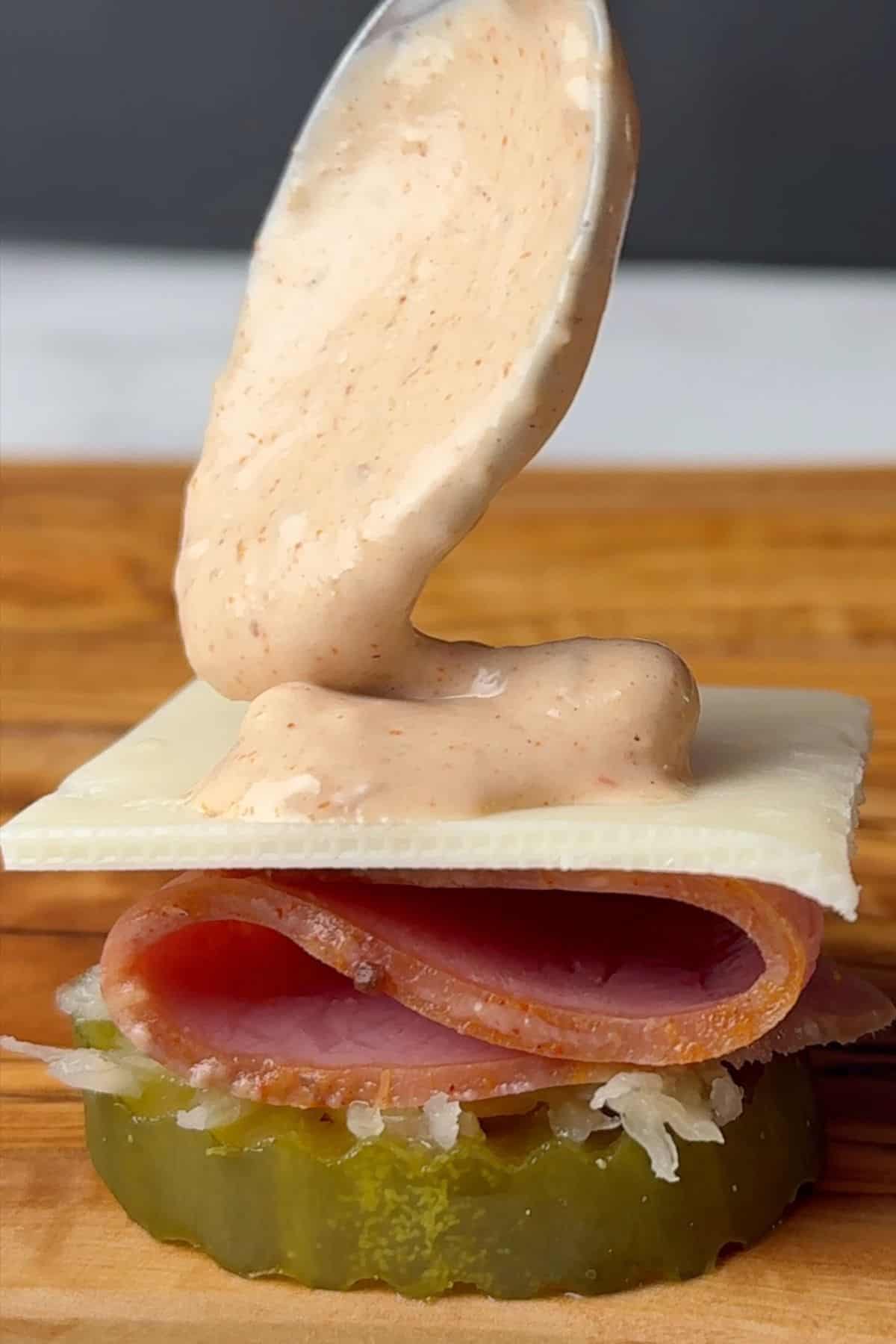 Spooning the Russian dressing onto one of the pickle bites.