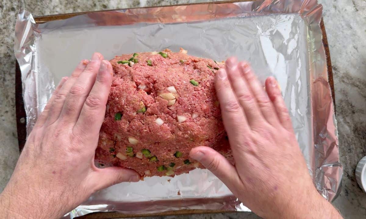 Shapping the meatloaf on a foil lined baking sheet.