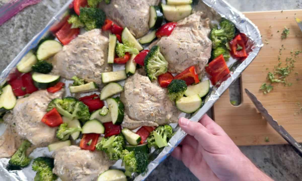 Low carb lemon garlic chicken with vegetables on a sheet pan before going in the oven.